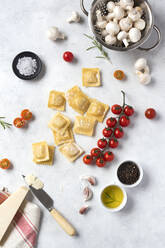 Von oben ungekochte Ravioli und verschiedene Gewürze mit Tomaten und Pilzen auf einem Tisch - ADSF00910