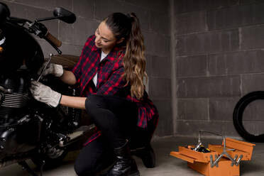 Woman repairing motorbike - FMOF01009
