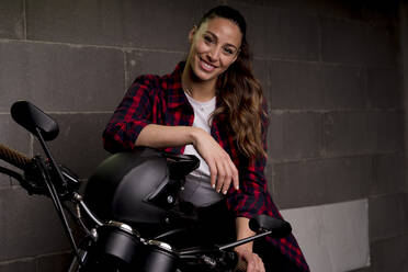 Junge lächelnde Frau auf einem Motorrad sitzend - FMOF01011