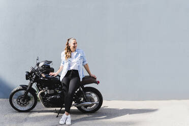 Lächelnde Frau auf Motorrad sitzend - FMOF01026