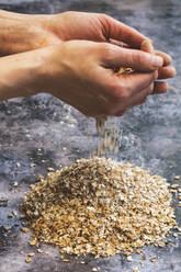 Die Hände voll mit speziellen Zutaten, Mehl und Körnern für Sauerteigbrot. - MINF14622