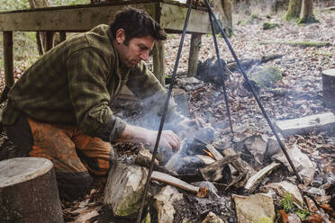 Man starting a camp fire in a forest. - MINF14629