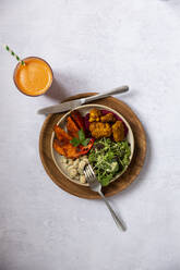 High angle close up of glass of carrot juice and bowl of mixed vegetables in a cafe. - MINF14633