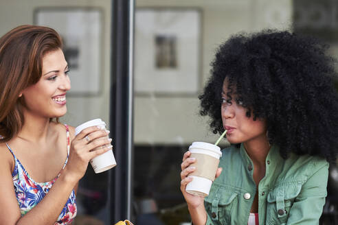 Freundinnen mit Kaffee zum Mitnehmen im Cafe - PGCF00088