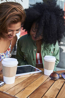 Girlfriends with coffee to go using tablet in cafe - PGCF00089