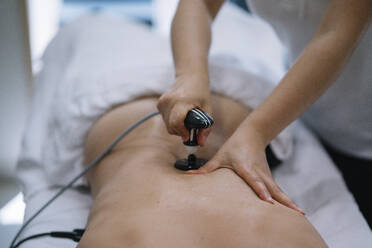 Die Physiotherapeutin behandelt einen Mann mit einem Gerät für die Radiotherapie - ADSF00977