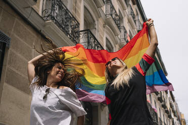 Couple lesbian woman with gay pride flag on the street of Madrid city - ADSF00987