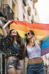 Couple lesbian woman with gay pride flag on the street of Madrid city - ADSF00994