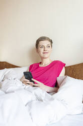 Schöne Frau schaut weg, während sie sich zu Hause auf dem Bett entspannt - TAMF02490