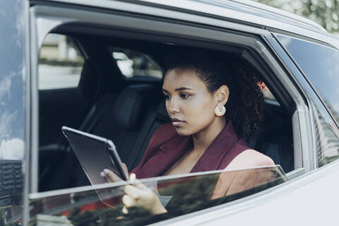 Young businesswoman using digital tablet seen through car window stock photo