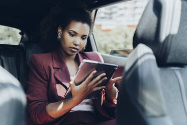 Young female entrepreneur using digital tablet while sitting in car - MTBF00557
