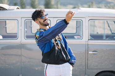 Lachender Mann mit Smartphone macht Selfie in der Nähe eines Lieferwagens - ADSF01003