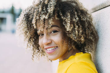 Portrait of smiling young woman leaning on wall - XLGF00350