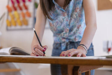 Junge weibliche Auszubildende, die an einer Werkbank im Atelier einen Entwurf zeichnet - EIF00076