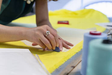 Weibliche Modedesignerin markiert auf gelbem Stoff im Atelier - EIF00088