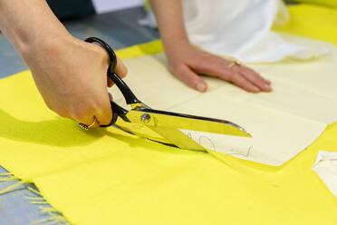 Hands of fashion entrepreneur cutting fabric at design studio - EIF00093