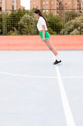 Attraktive Frau in Sportkleidung, die gerade auf einem Sportplatz in der Stadt nach vorne fällt - ADSF01186