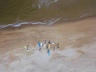 Aerial view of surfers preparing at sandy coastal beach - KNTF04959