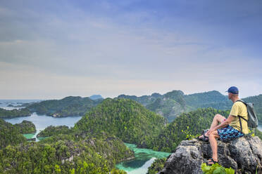 A tourist looking out over a bay of islands from Harfat mountain, Spice Islands, West Papua, Indonesia, Southeast Asia, Asia - RHPLF15417