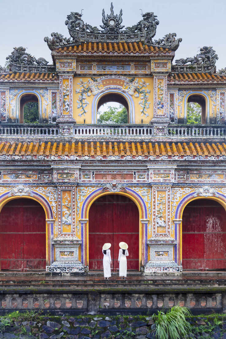 Two young women in traditional dress standing at the Western gateway to the  Purple Forbidden City, Hue, Vietnam, Indochina, Southeast Asia, Asia stock  photo