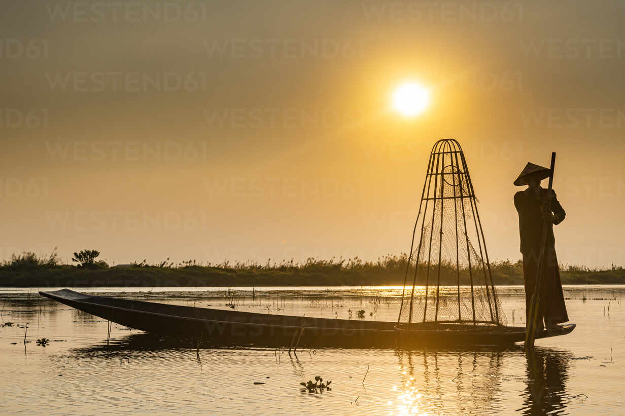 Fishermen in boat at sunrise, silhouettes of people on lake or