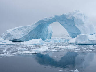Ein riesiger Bogen, der sich in einem gekippten Eisberg in der Cierva-Bucht gebildet hat, Antarktis, Polarregionen - RHPLF15655