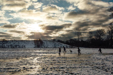 Auf Eis spielende Kinder auf einem Feld mit Morgensonne - CAVF86889