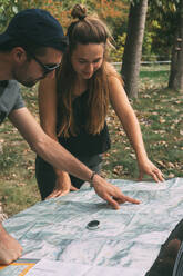 Junge und Mädchen planen die Route auf einer Karte und einem Kompass - CAVF86905