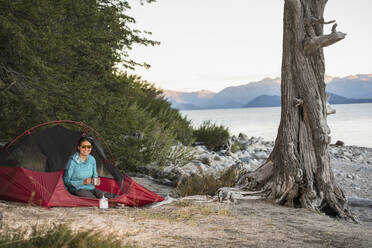 Woman relaxing at camp at the Nahuel Huapi Lake in Patagonia - CAVF86991