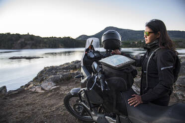 Frau steht neben einem Tourenmotorrad am Lago Alumine in Argentinien - CAVF87010