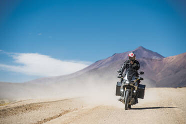 Mann auf Tourenmotorrad auf staubiger Straße in Bolivien - CAVF87022