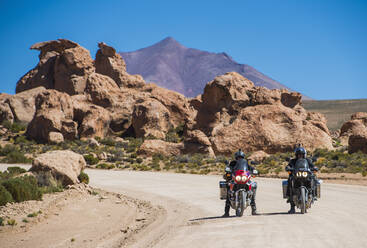 Zwei Freunde auf einem Tourenmotorrad auf einer staubigen Straße in Bolivien - CAVF87023