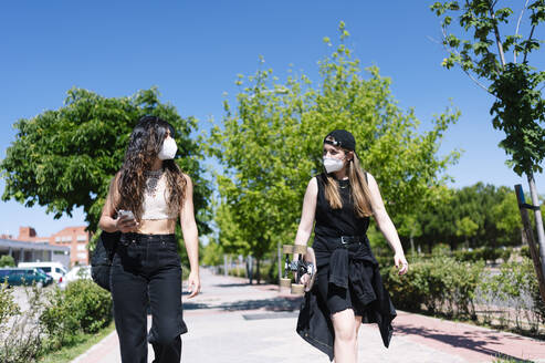 Two women with protective face masks walking in the street - JCMF00972