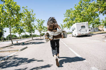 Unbekümmerte junge Frau mit Skateboard auf der Straße, Rückansicht - JCMF00980