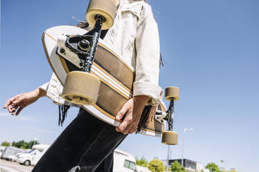 Unbekümmerte junge Frau mit Skateboard auf der Straße - JCMF00982