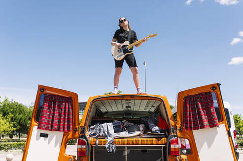 Junge Frau spielt Gitarre, stehend auf offenem Lieferwagen - JCMF00992