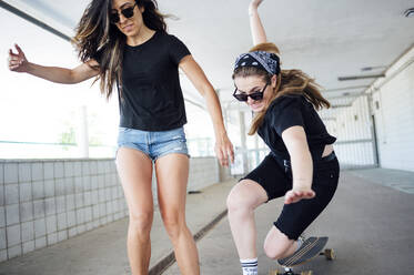Junge Frau, die in einer Unterführung Skateboard fährt - JCMF00994