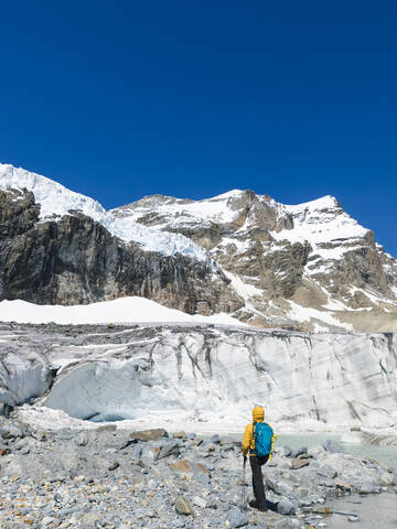 Man hiking while exploring snowcapped mountain against clear blue sky stock photo