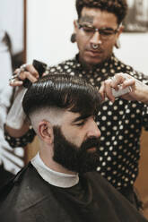 Trendiger Friseur, der einem Mann im Salon die Haare stylt - XLGF00370