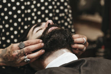 Friseur stylt den Bart eines Kunden im Salon - XLGF00376