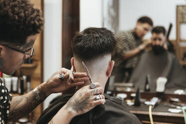 Trendiger Friseur, der einem Mann im Salon die Haare schneidet - XLGF00378