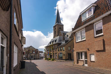 Niederlande, Südholland, Noordwijk, Leere Stadtstraße mit Kirchturm im Hintergrund - TAMF02512