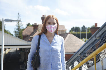 Junge Frau mit Gesichtsschutzmaske am Bahnhof - PMF01167