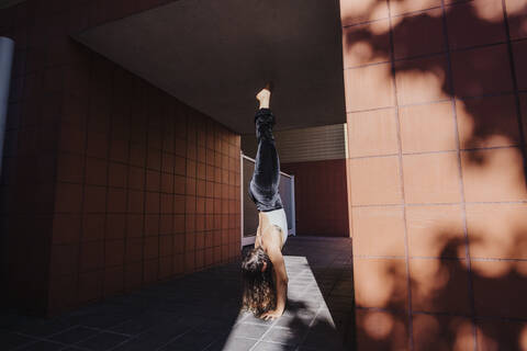 Young woman performing handstand in tunnel during sunny day stock photo