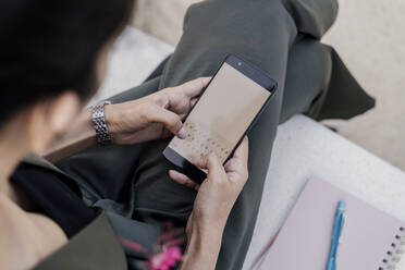 Close-up of female professional using smart phone while sitting on seat - AFVF06758