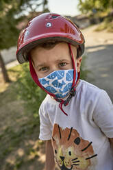 Nahaufnahme eines Jungen mit Maske und rotem Helm, der im Freien steht - VEGF02507