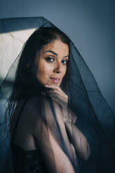 Close-up of young woman wearing black veil standing against wall at home - DCRF00380