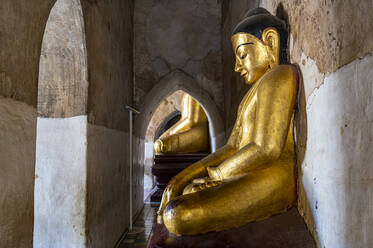 Myanmar, Mandalay Region, Bagan, Gold colored statue of meditating Buddha inside Manuha Temple - RUNF03861