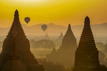 Myanmar, Region Mandalay, Bagan, Heißluftballons fliegen über alte Stupas in der nebligen Abenddämmerung - RUNF03867