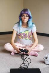 Trendy blauhaarige Frau spielt Videospiel zu Hause - JMPF00149
